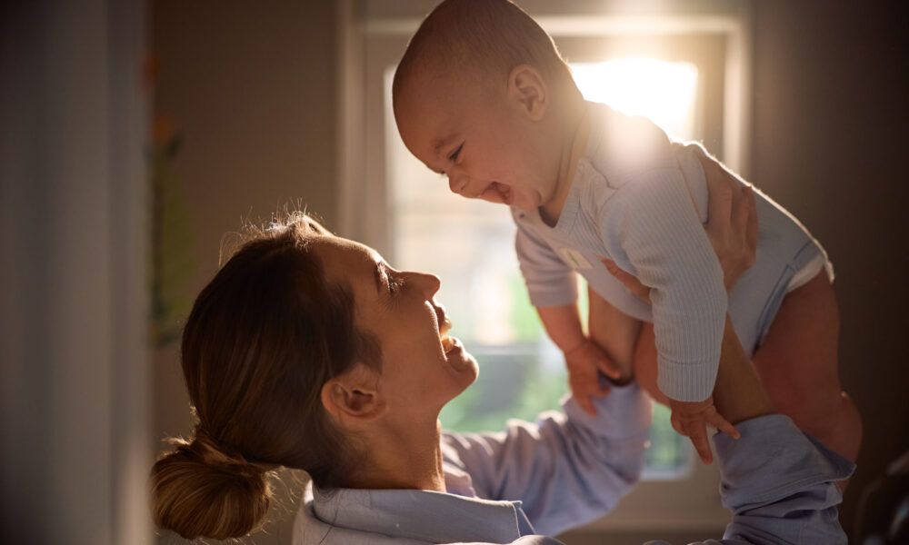 Cheerful baby boy having fun with his mother at home.